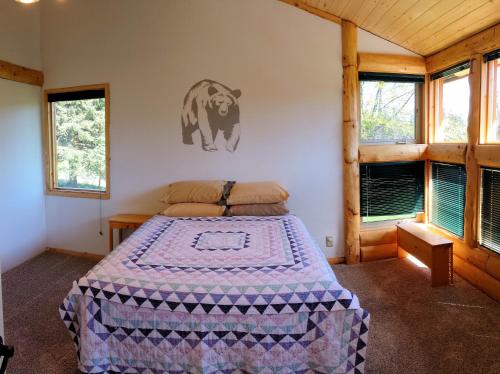 Schlafzimmer mit einem Bett mit einem Bärenbild an der Wand in der Unterkunft Bear Den Vacation Home in Anchor Point