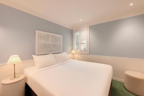 a white bedroom with a large white bed and a window at Adina Apartment Hotel Chippendale in Sydney