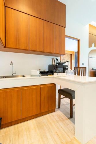 a kitchen with wooden cabinets and a white counter top at Tajh Pool Villas in Chalong 