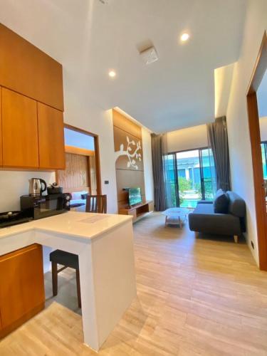 a kitchen and living room with a table and a couch at Tajh Pool Villas in Chalong 