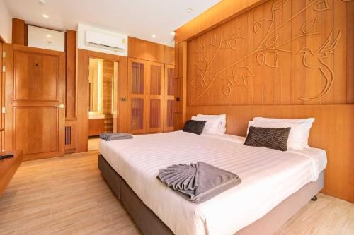 a bedroom with a large bed with a wooden headboard at Tajh Pool Villas in Chalong 