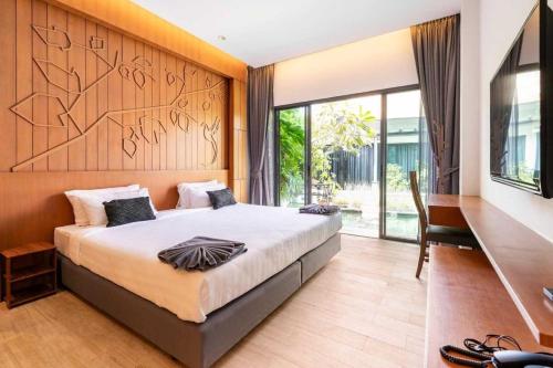 a bedroom with a large bed and a desk and window at Tajh Pool Villas in Chalong 