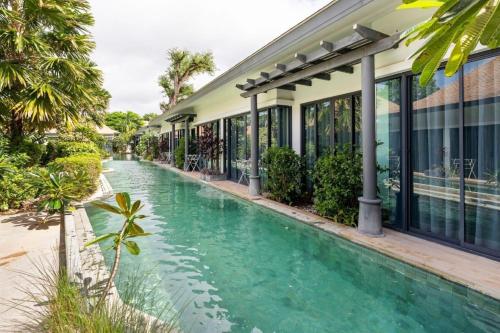 a swimming pool in front of a building at Tajh Pool Villas in Chalong 