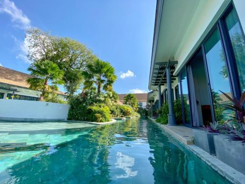 a house with a swimming pool next to a building at Tajh Pool Villas in Chalong 