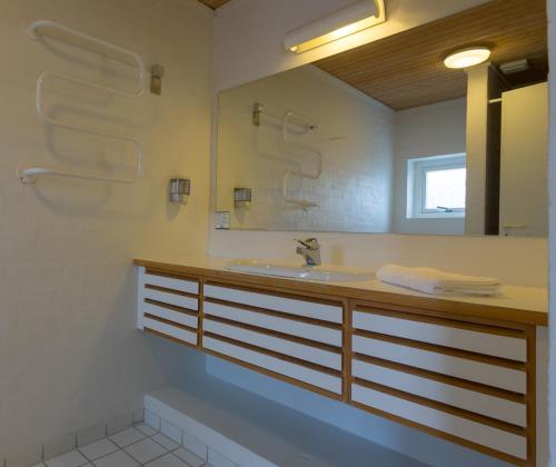 ein Bad mit einem Waschbecken und einem Spiegel in der Unterkunft Skagen Strand Holiday Center in Hulsig