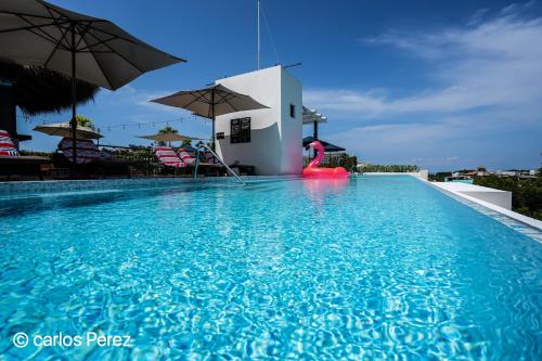 a swimming pool with blue water and an umbrella at Hotel Puerto Sayulita in Sayulita