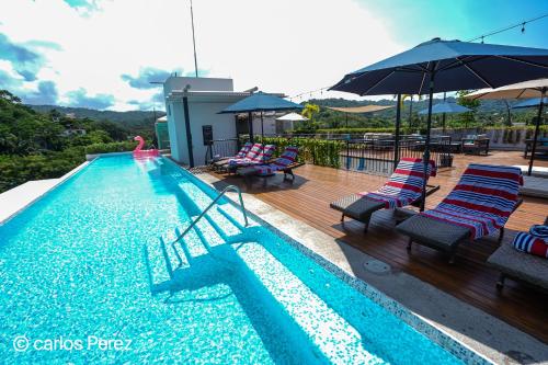 a swimming pool with chairs and umbrellas on a deck at Hotel Puerto Sayulita in Sayulita