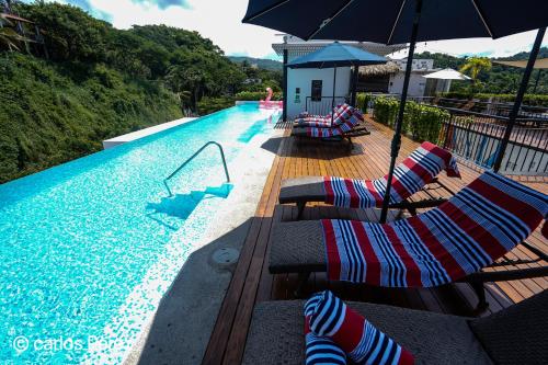 a swimming pool with lounge chairs and an umbrella at Hotel Puerto Sayulita in Sayulita