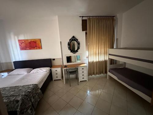ポッツオーリにあるHotel Le Pinede Vistamareのベッドとデスクが備わるホテルルームです。