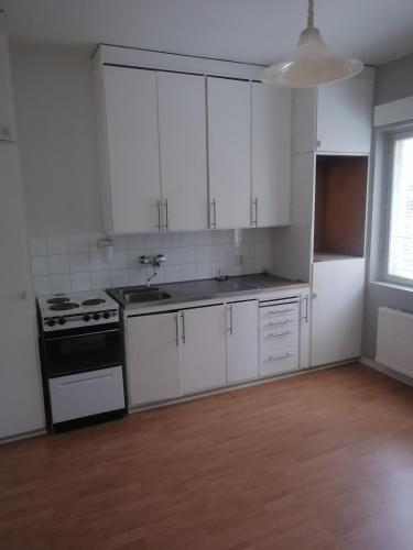an empty kitchen with white cabinets and a stove at Apartments 15-20 block D in Kouvola