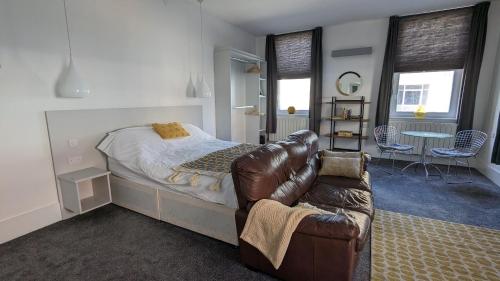 a bedroom with a bed and a leather couch at Gorgeous comfortable Apartment on the High Street in Merthyr Tydfil