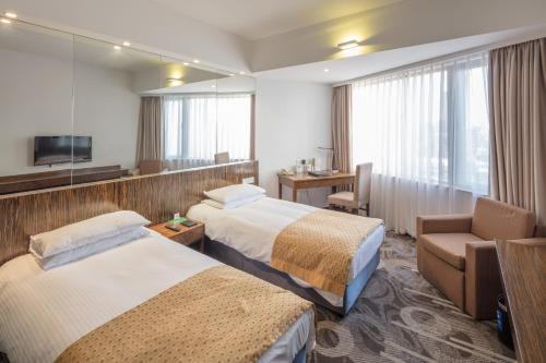 a hotel room with two beds and a chair at City Hotel Shanghai in Shanghai