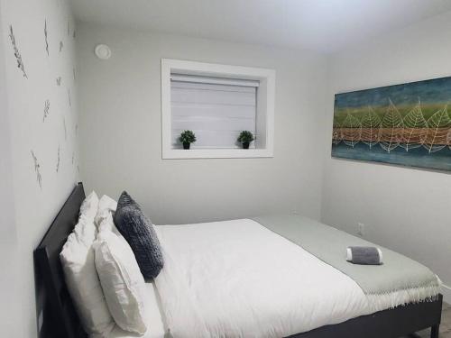 ein Schlafzimmer mit einem Bett und einem Fenster mit zwei Pflanzen in der Unterkunft Lux Modern 2BR Radiant Suite+Free Parking in Delta