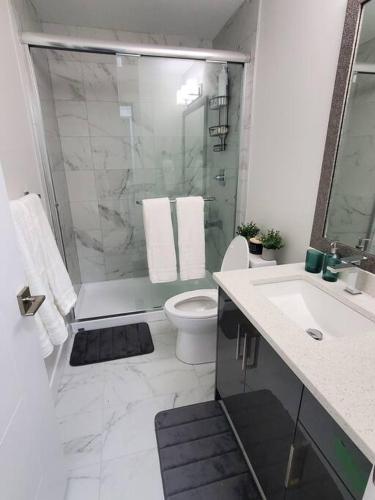 a bathroom with a shower and a toilet and a sink at Lux Modern 2BR Radiant Suite+Free Parking in Delta