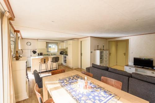 uma sala de estar com uma mesa e um sofá em Luxe familiehuis Veluwe 4-6 persons Pool Kids Dog em Hoenderloo