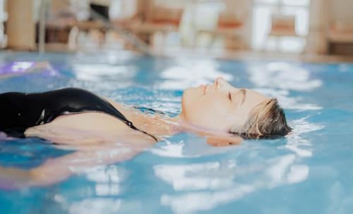 a young woman swimming in a swimming pool at Hotel Dirsch Wellness & Spa Resort in Emsing