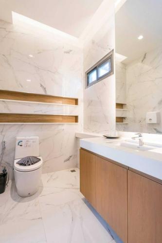 a white bathroom with a toilet and a sink at Tajh Pool Villas in Chalong 