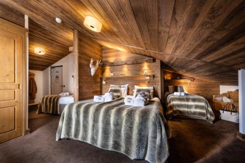 a bedroom with two beds and a wooden ceiling at Hôtel Ski Lodge - Chambres & Appartements - Village Montana in Val dʼIsère