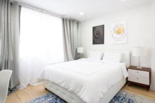 a white bedroom with a bed and a large window at Magnificent 3 BR Apartment in New York