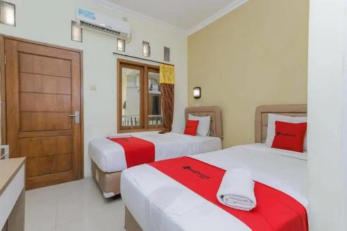 a bedroom with two beds with red and white sheets at OYO 91292 Pondok Inap Shofwa 1 in Sidoarjo