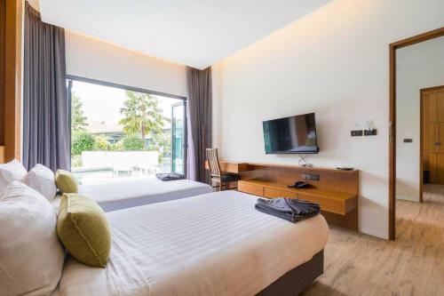 a hotel room with a large bed and a television at Tajh Pool Villas in Chalong 