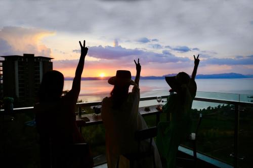 a group of people standing on a balcony with their arms up at Colorful Yunnan Absolutely Beautiful Dian B&B in Kunming