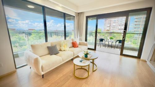 a living room with a white couch and large windows at Colorful Yunnan Absolutely Beautiful Dian B&B in Kunming