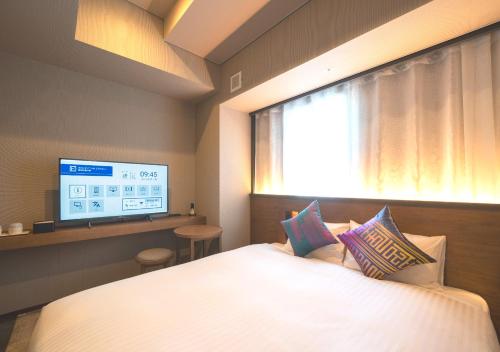 a bedroom with a large bed with a window and a tv at Hotel Oriental Express Fukuoka Nakasu Kawabata in Fukuoka