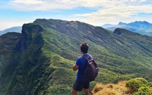 a man with a backpack standing on top of a mountain at The Grove in Kandy