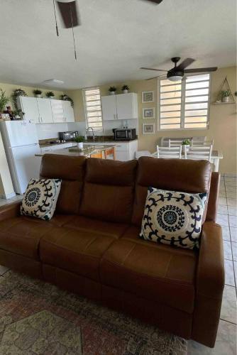a living room with a brown couch and a kitchen at Oceanfront Retreat in Playa Fortuna, Puerto Rico in Luquillo