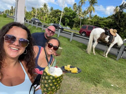 two women and a man posing with a drink and a horse at Oceanfront Retreat in Playa Fortuna, Puerto Rico in Luquillo