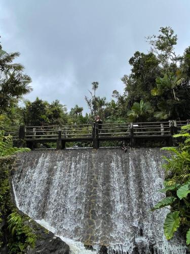 a person standing on a bridge over a waterfall at Oceanfront Retreat in Playa Fortuna, Puerto Rico in Luquillo
