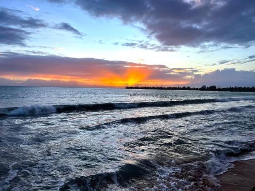 a sunset over the ocean with waves at Oceanfront Retreat in Playa Fortuna, Puerto Rico in Luquillo