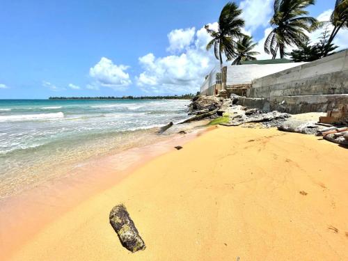 a beach with a rock in the sand and the ocean at Oceanfront Retreat in Playa Fortuna, Puerto Rico in Luquillo