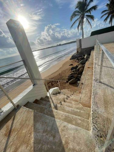 a staircase leading to the beach with a palm tree at Oceanfront Retreat in Playa Fortuna, Puerto Rico in Luquillo