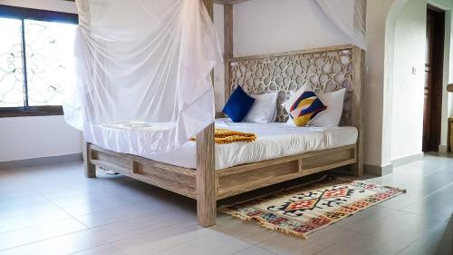 a bedroom with a wooden bed with a canopy at Relaxing Beach Front Villa in Mambrui