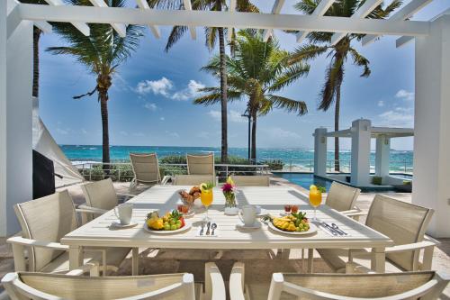 a table with food and drinks on a patio with the beach at Oceanfront 5-Stars Starfish Villa, Dawn Beach, Private Pool, Secured, Concierge in Oyster Pond