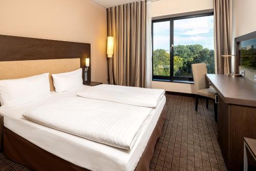 a hotel room with a bed and a desk and a window at IntercityHotel Hamburg Dammtor-Messe in Hamburg