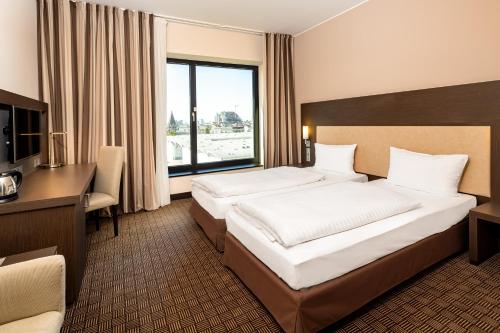 a hotel room with two beds and a desk at IntercityHotel Hamburg Dammtor-Messe in Hamburg