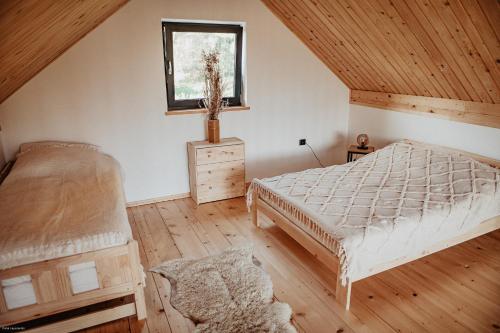 a attic bedroom with a bed and a window at Cichosza domki w Pieninach in Grywałd