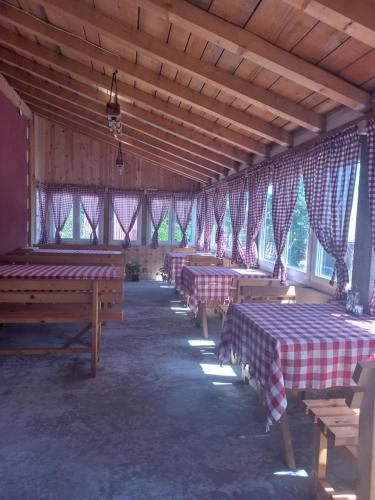 una habitación con filas de mesas en un granero con ventanas en Apartmani Sobe Sljivancanin, en Žabljak