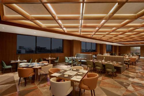 un restaurante con mesas, sillas y ventanas en Doubletree By Hilton Varanasi en Varanasi