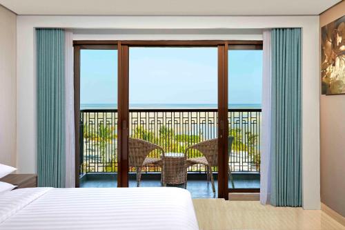 a bedroom with a bed and a balcony with a table at Fairfield by Marriott Belitung in Tanjungpandan