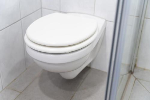 a white toilet in a white tiled bathroom at Kleines Häuschen für Monteure in Wörrstadt