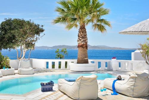a swimming pool with lounge chairs and a palm tree at Saint John Hotel Villas & Spa in Agios Ioannis Mykonos