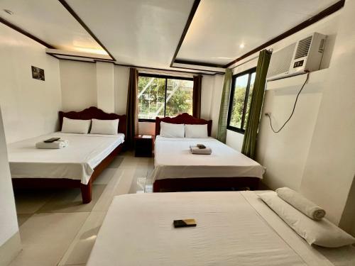 ein Hotelzimmer mit 2 Betten und einem TV in der Unterkunft Alocasia El Nido in El Nido