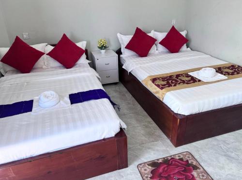 two beds in a room with red and blue pillows at Kro Nhep Guesthouse in Kampot
