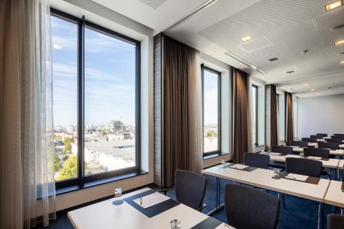 a conference room with tables and chairs and large windows at IntercityHotel Hamburg Dammtor-Messe in Hamburg