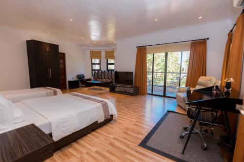 ein Schlafzimmer mit einem Bett und einem Schreibtisch sowie ein Wohnzimmer in der Unterkunft Bellagio Hills Hotel and Restaurant in Paoay