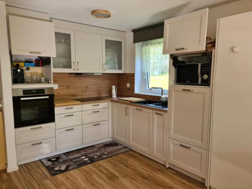 a kitchen with white cabinets and a sink at Apartments Haus Quelle in Leukerbad